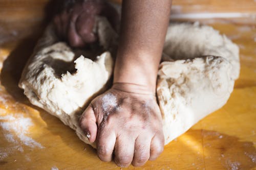 Person Kneading the Dough on Wooden Surface