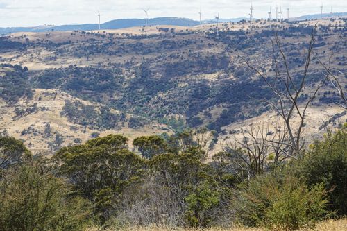 Free Expansive view of rolling hills and wind turbines under a clear sky, showcasing renewable energy setup. Stock Photo