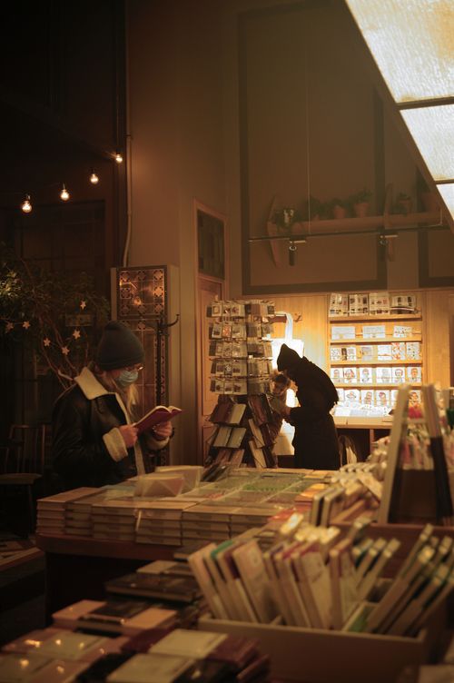 Free Warmly lit bookstore with people browsing and reading books in an intimate setting. Stock Photo
