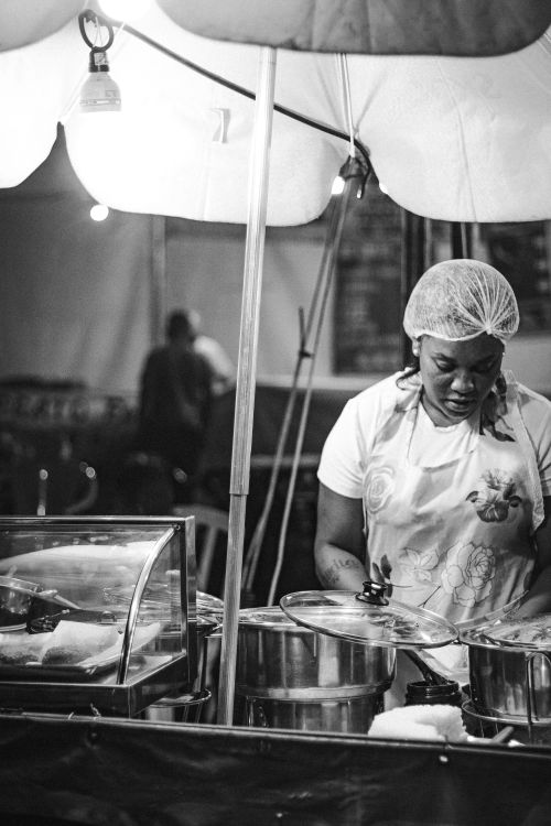 Free Black and white photo of a female street food vendor in Brasília night market. Stock Photo