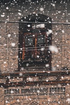 Captivating view of snowflakes falling against a historic brick building facade, showcasing winter's beauty.