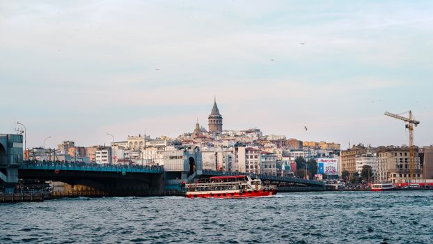 The historic Galata Tower overlooking the busy Bosphorus in Istanbul, Turkey with a ferry boat passing by.