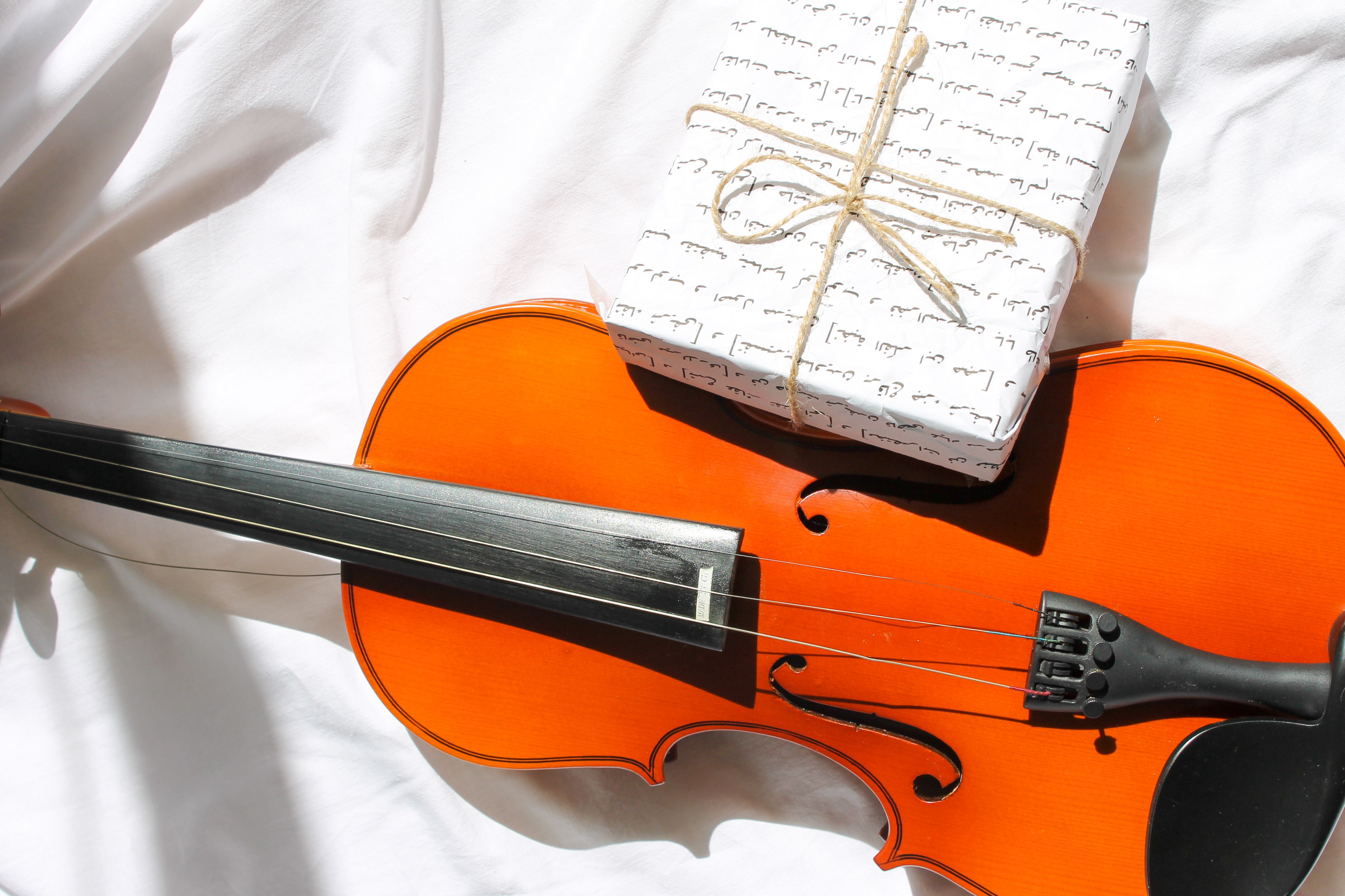 A bright violin paired with a music-themed gift box on a white fabric surface.