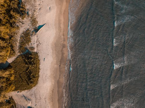 Free Stunning aerial shot showcasing a beautiful beach with lush greenery and clear ocean waves. Stock Photo