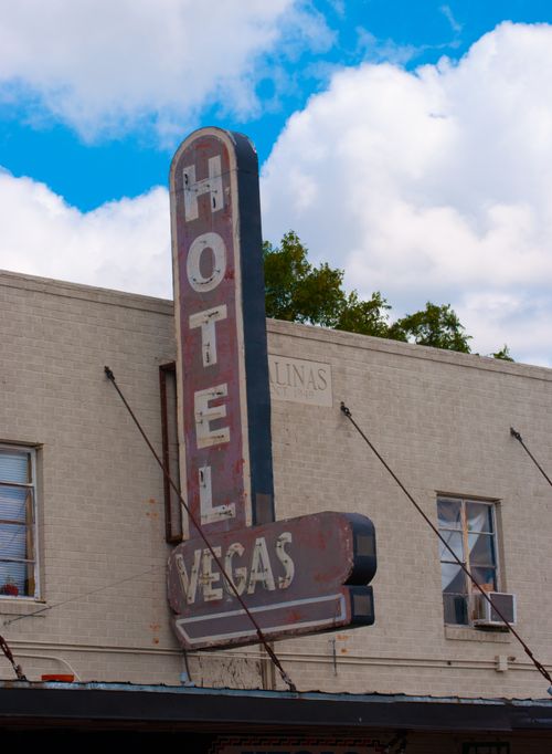 Free Vintage Hotel Vegas sign on building facade with cloudy blue sky. Stock Photo