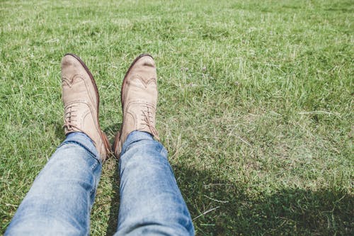 穿著藍色牛仔牛仔褲，坐在草地上的人