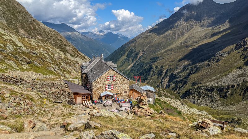 Charming stone hut in the Austrian Alps offers a stunning view of the valley and mountains.
