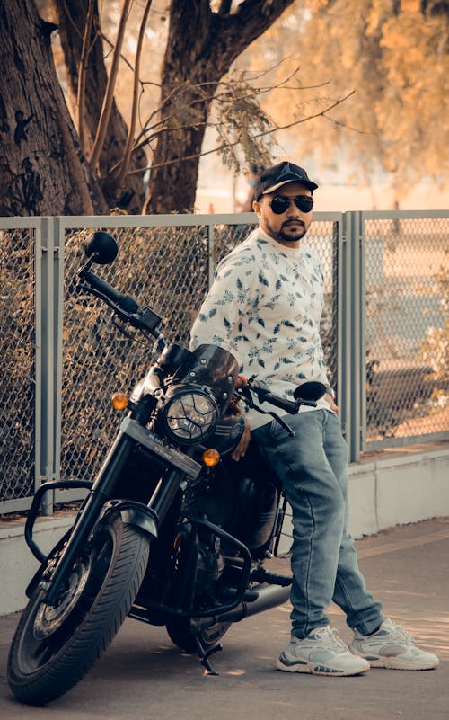 Man in White and Black Long Sleeve Shirt Sitting beside Black Motorcycle