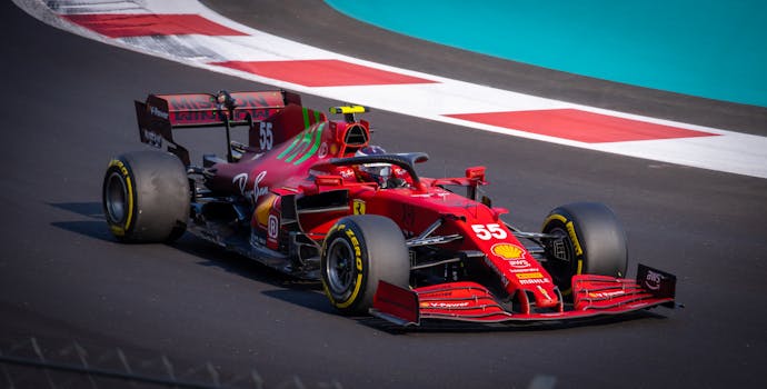 Red racing car speeding on an asphalt circuit, showcasing dynamic motion and precision.