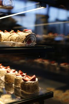 Scrumptious strawberry desserts elegantly displayed in a glass cabinet, captured beautifully indoors.