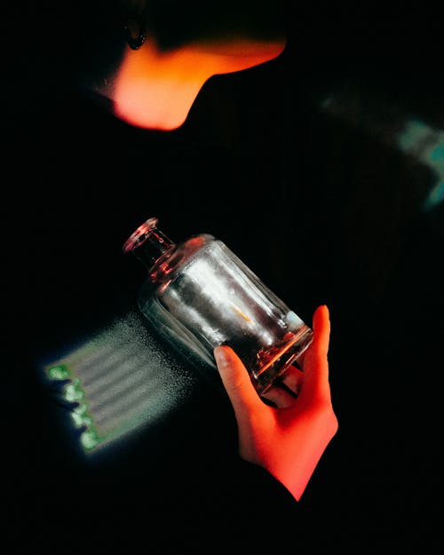 Person Holding Clear Glass Bottle