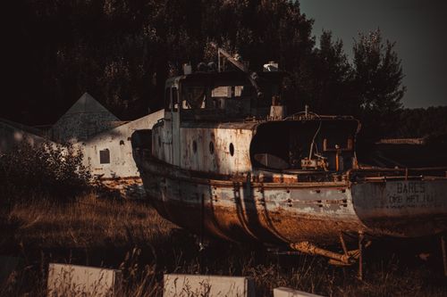 Free An abandoned rusty shipwreck surrounded by grass, giving a moody and decaying feel outdoors. Stock Photo