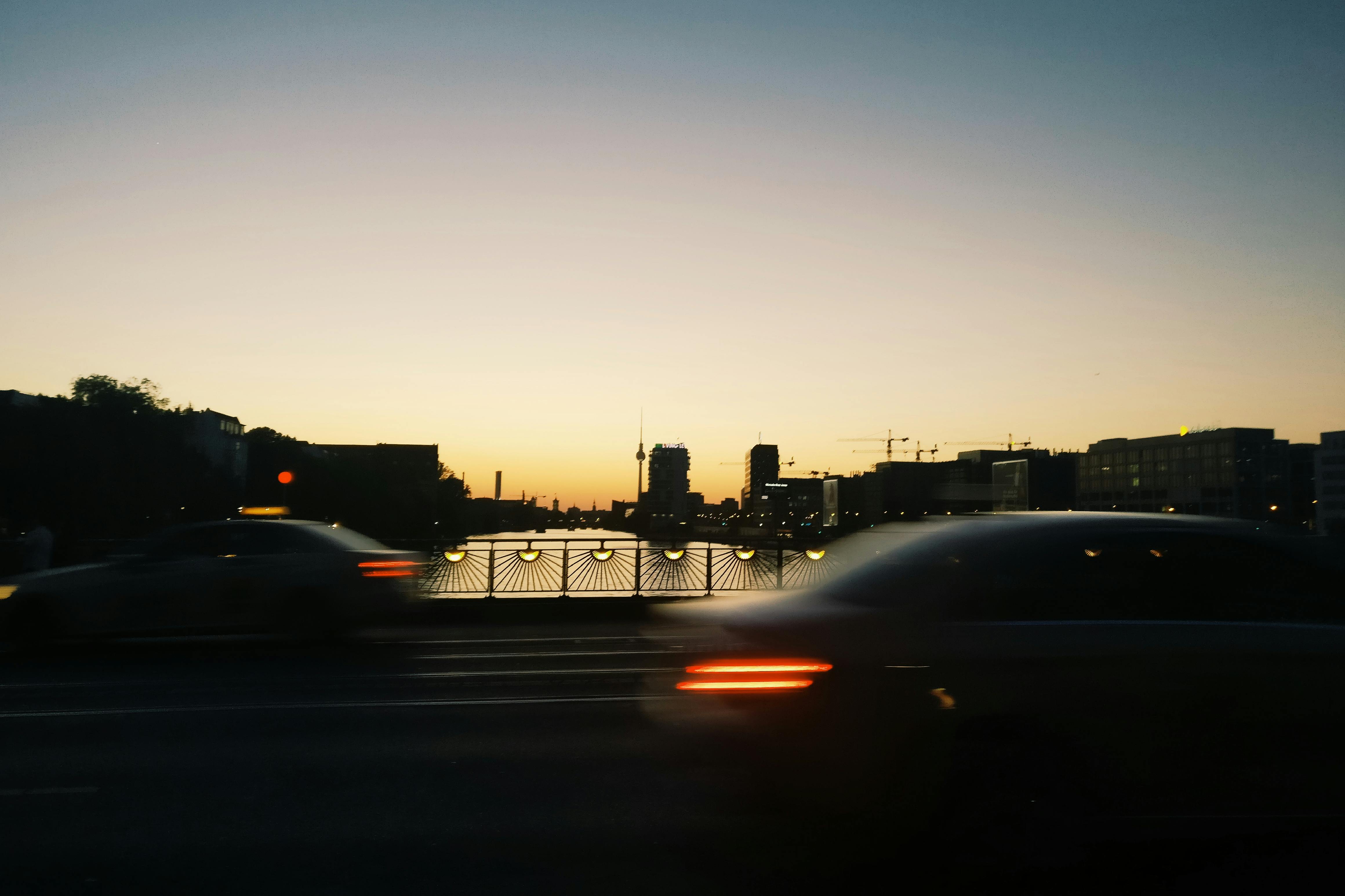 黄昏时分，一辆模糊的汽车穿过柏林的一座桥，背景是城市天际线