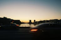 黄昏时分，一辆模糊的汽车穿过柏林的一座桥，背景是城市天际线