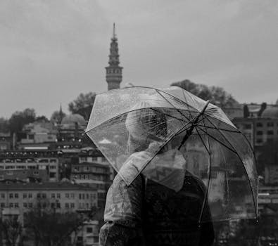 Person with umbrella overlooking Istanbul skyline on a rainy day.