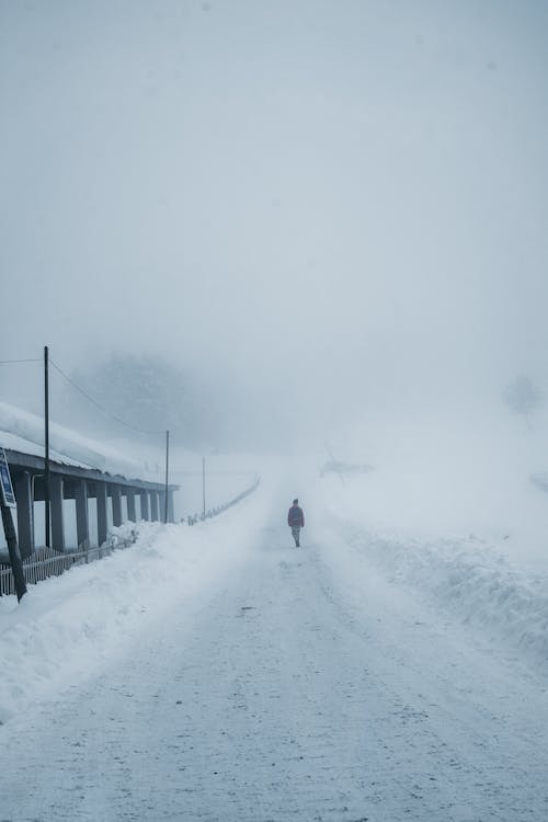 Person Walking on Snow Covered Road