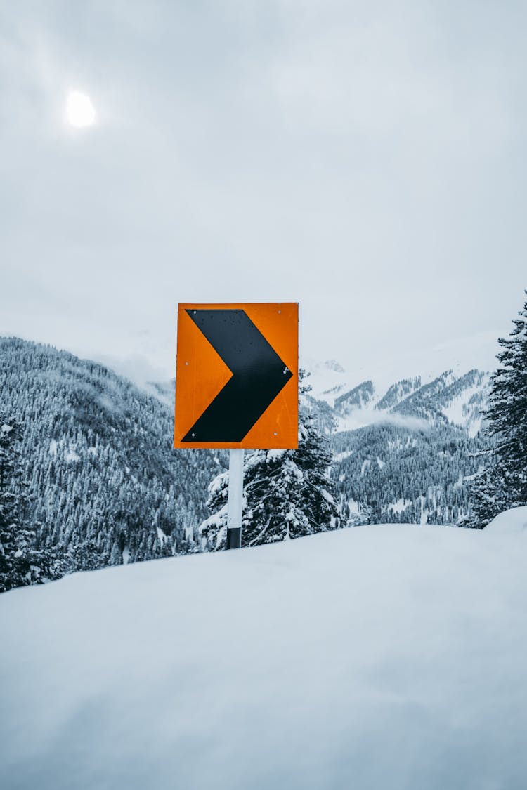 Road Sign On Snow Hill In Mountains