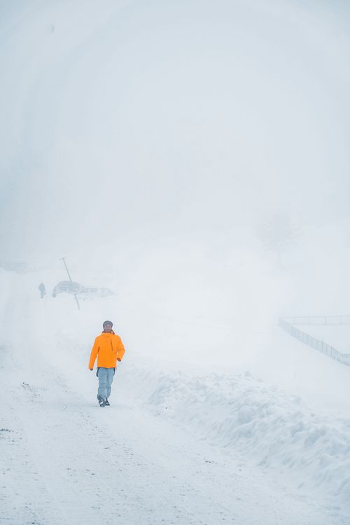 Free A person walks through a foggy, snow-covered winter landscape in bright clothing. Stock Photo