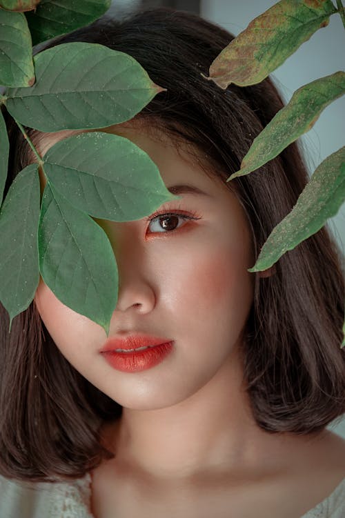 Free Close-Up Photography of a Woman Near Leaves Stock Photo