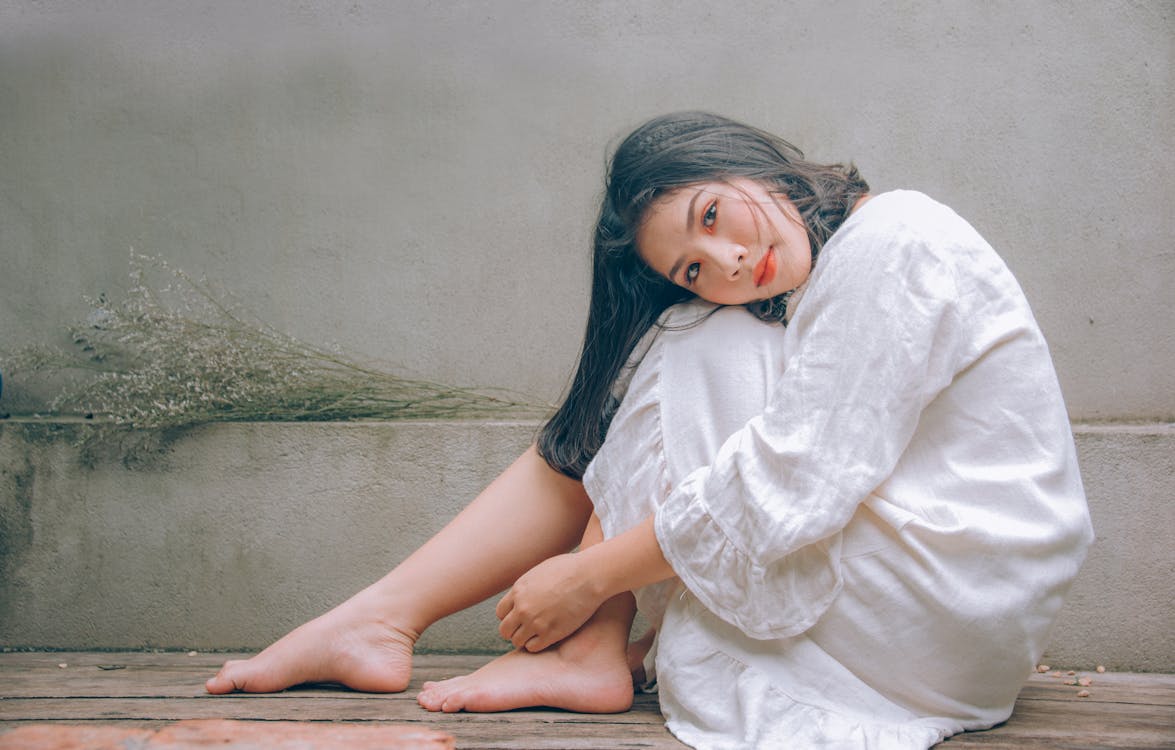 Free Woman Wearing White Dress Sitting on Wooden Floor Stock Photo