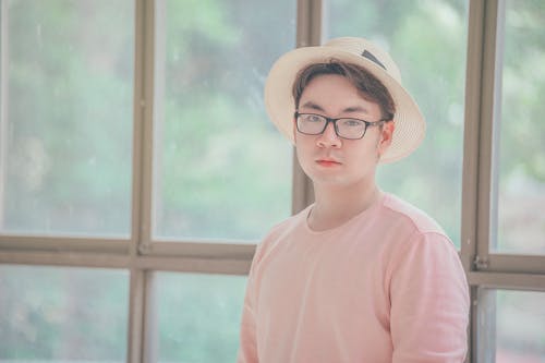 Man Wearing Pink Top Standing Near Glass Panel