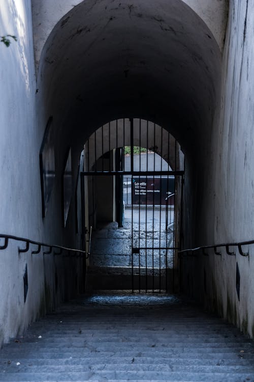 View of a Stairs in an Arched Tunnel with a Gate at the Bottom 