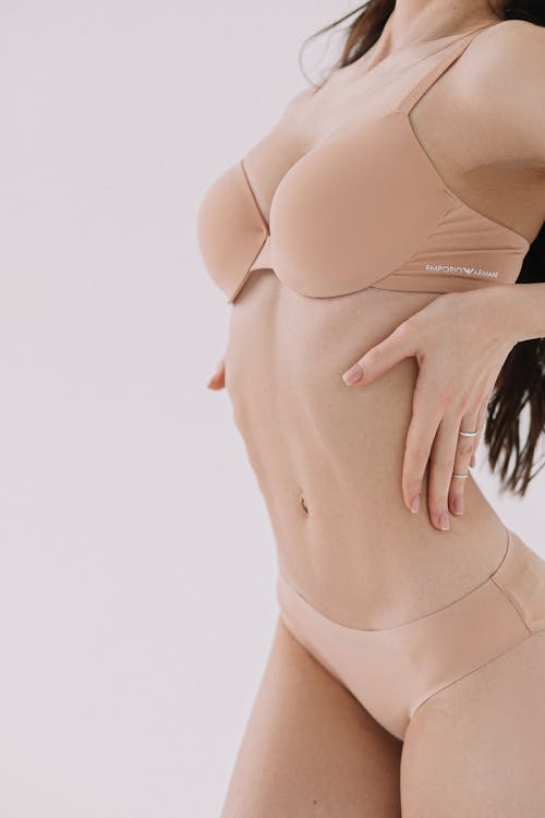 Cropped view of a woman in beige underwear laying her hands on her