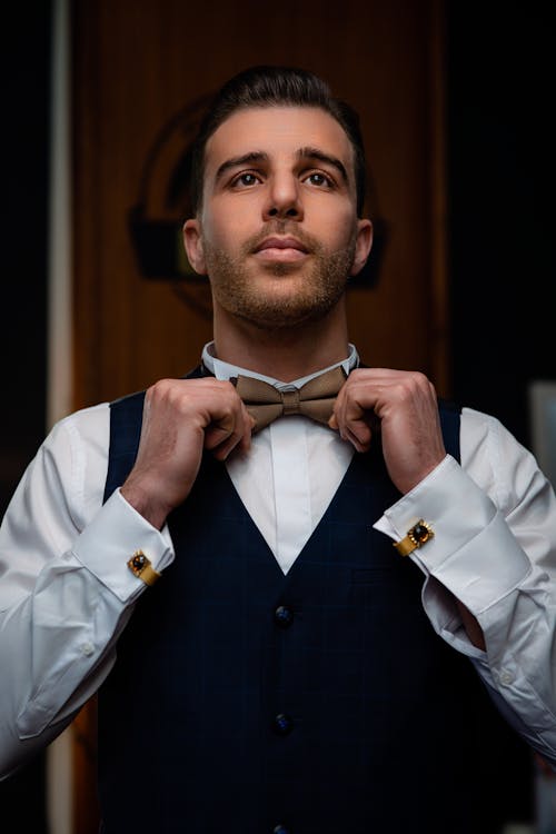 Elegant Man Fixing his Brown Bow Tie 