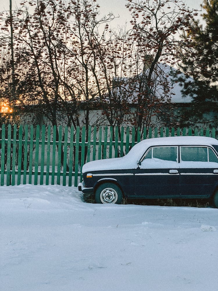 Car Parked Next To Picket Fence In Snow