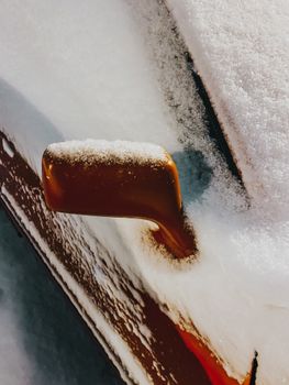 Close-up of a car side mirror covered in frost and snow, capturing winter's chill.