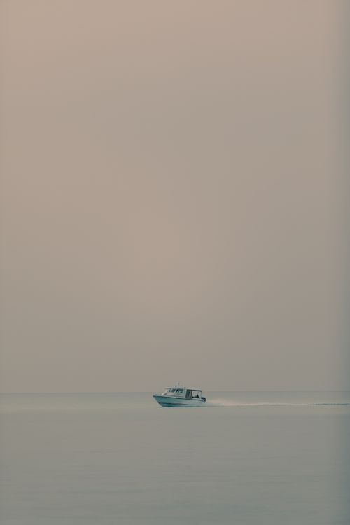 Free Minimalist scene of a boat gliding across a calm sea under a clear sky, perfect for peaceful and serene themes. Stock Photo