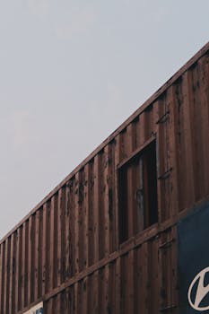 Vertical shot of a rusty brown shipping container under a clear sky, providing ample copy space.
