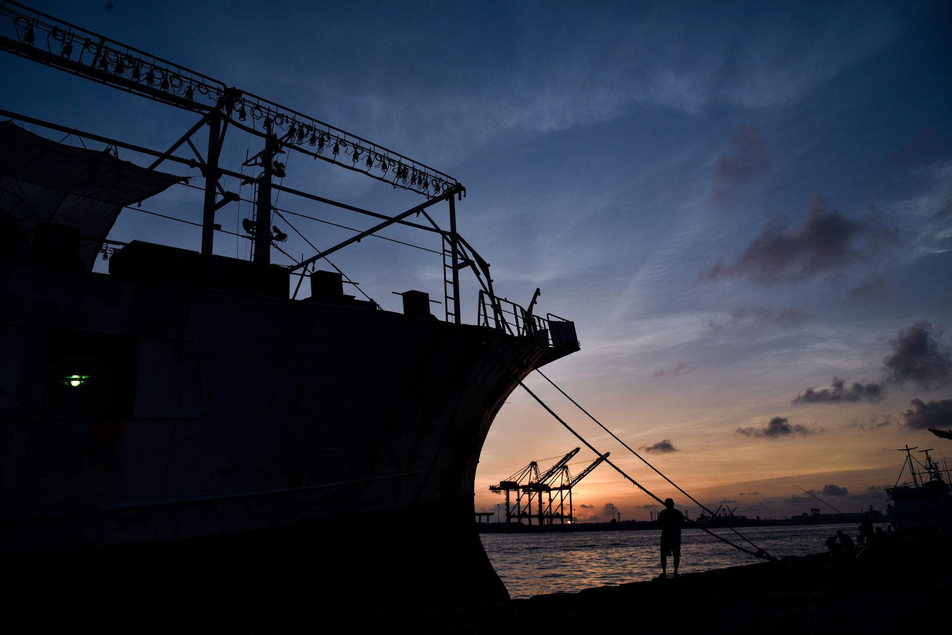 Dramatic silhouette of a ship docked at a harbor during sunset, showcasing maritime tranquility.