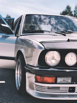 一辆银色老式汽车的特写，展示了经典的圆形前灯和闪亮的镀铬元素