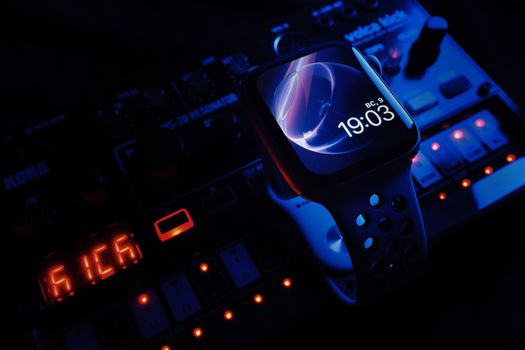 A smart watch with a digital display on a mixing console, showcasing a technology-meets-music theme.