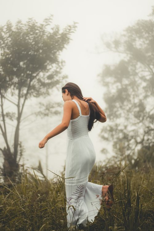 Free Woman in a white dress walking outdoors in a misty forest, creating a serene and mystical atmosphere. Stock Photo