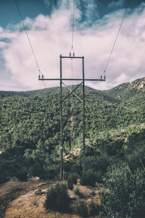 Free Utility pole and power lines against a lush mountain backdrop on a cloudy day. Stock Photo