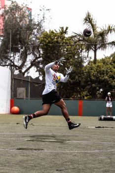 A young athlete leaps to catch a football on an outdoor field, showcasing agility and skill.
