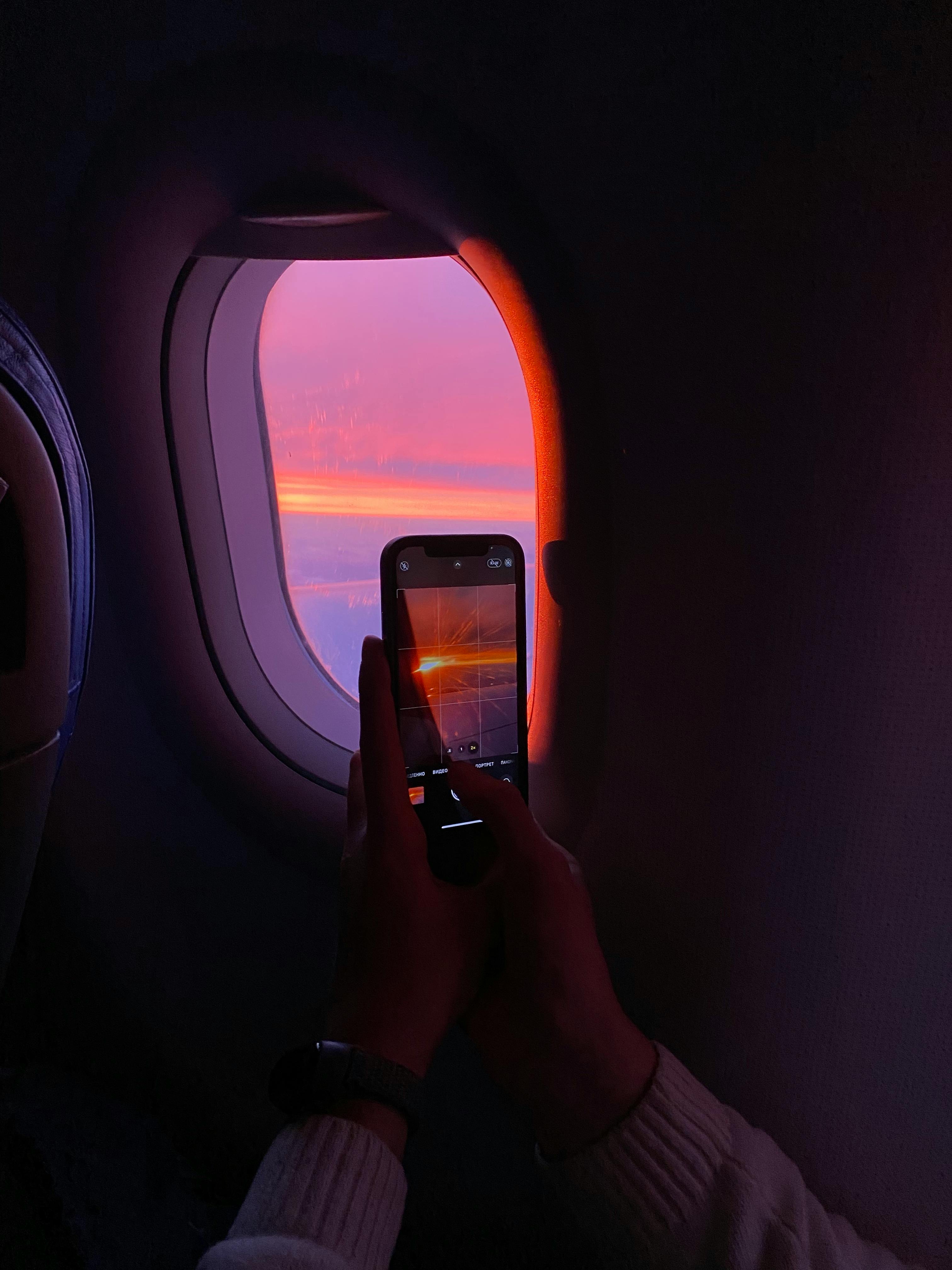 A stunning sunset view captured through an airplane window using a smartphone.