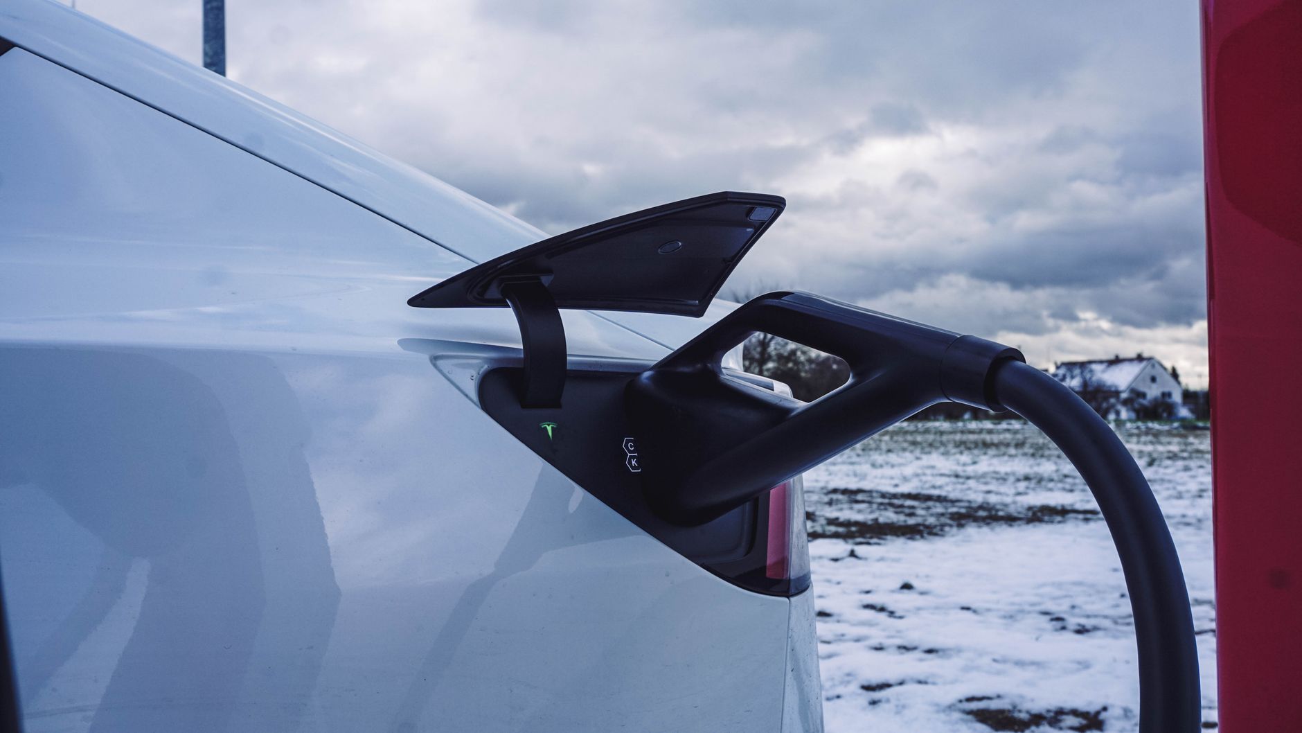 White electric car charging outdoors in a snowy winter landscape