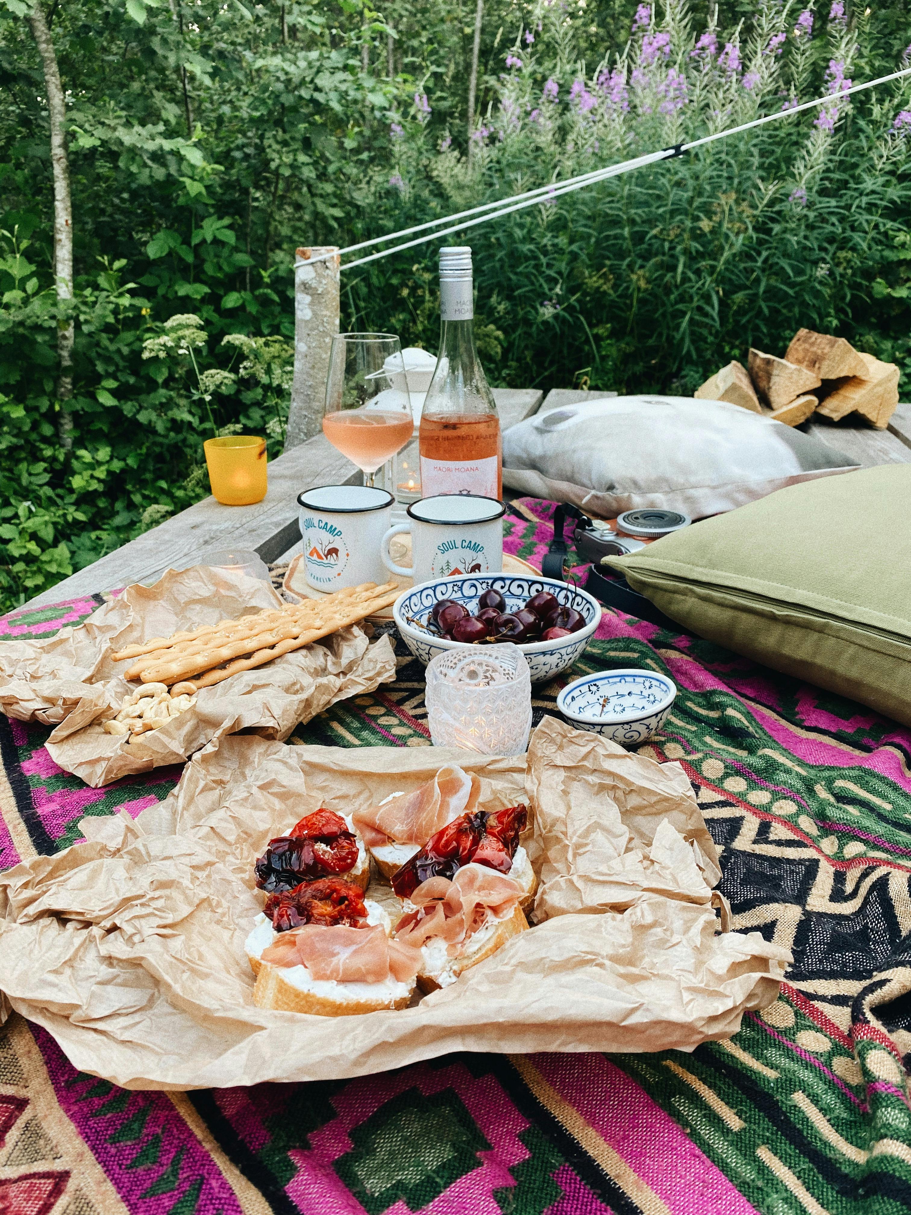 Rustic picnic setting with charcuterie and wine in a lush Karelian forest.