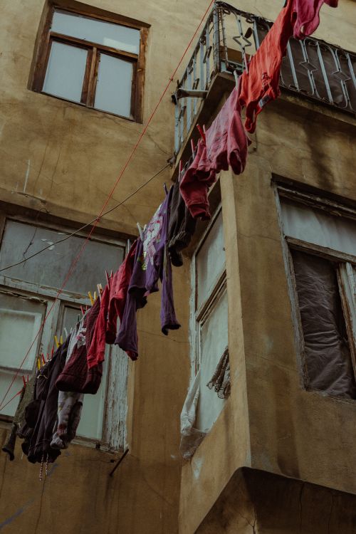 Free Low angle view of colorful clothes hanging on a line in an urban alleyway, evoking a rustic city vibe. Stock Photo