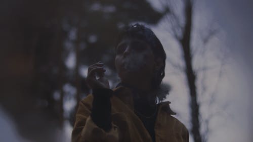 Low Angle Shot of a Person in Brown Jacket Smoking Cigarette