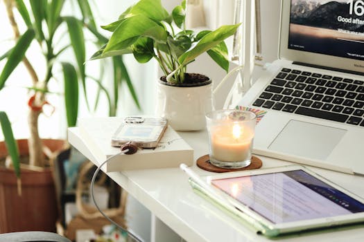 A serene home office desk setup with a laptop, candle, and plants creating a peaceful ambiance.