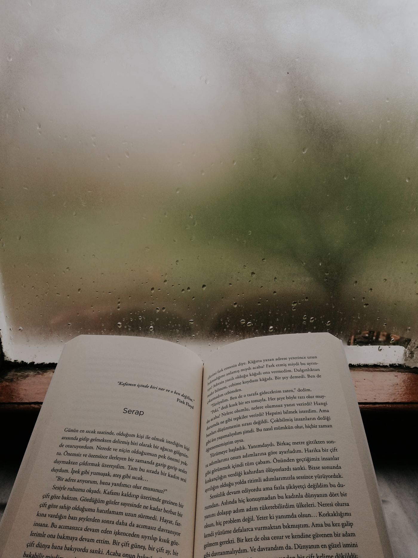 Открытая книга у окна с каплями дождя