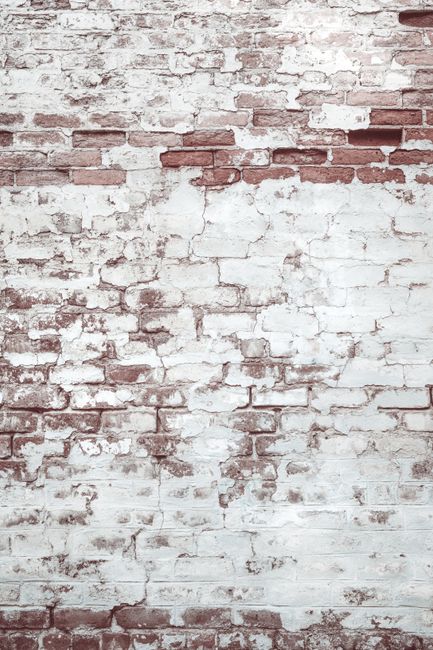 A distressed brick wall with peeling white paint, showcasing a rustic texture in Savannah, GA.