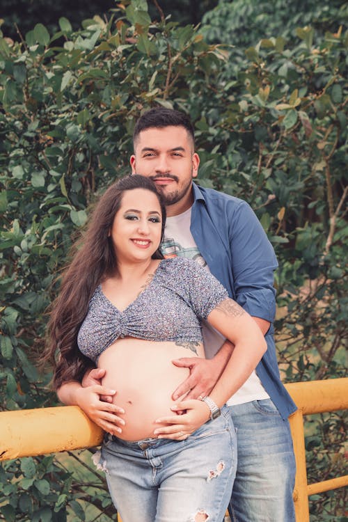 Free A Man Standing Behind the Pregnant Woman while Touching Her Belly Stock Photo