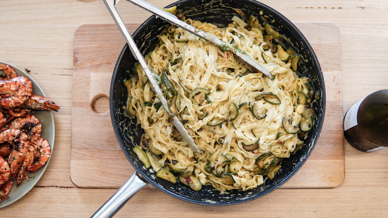 Padella nera con tagliatelle cremose mantecate e salsa lucida