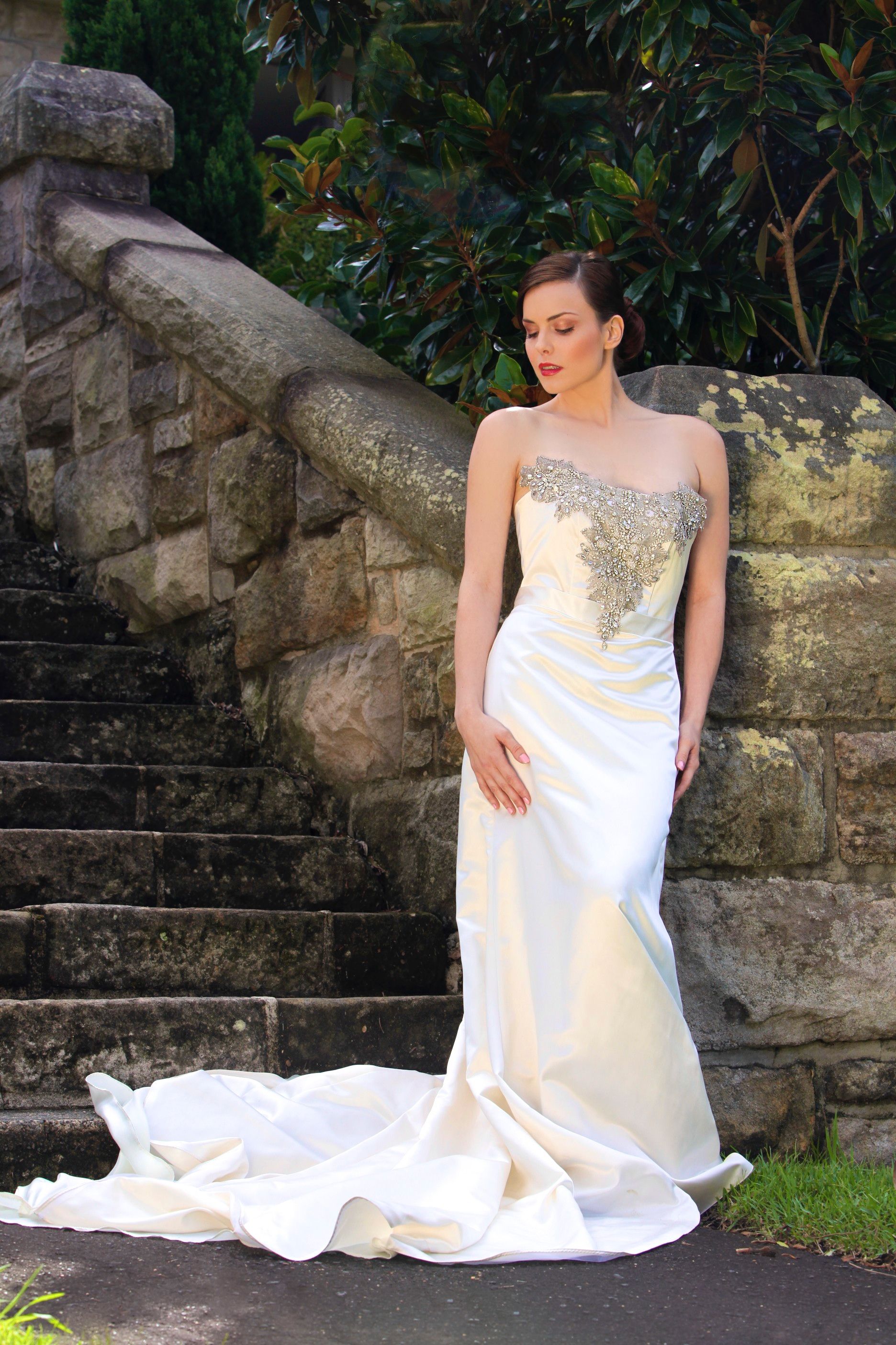 A bride elegantly poses in a wedding dress by a stone staircase, exuding beauty and grace.