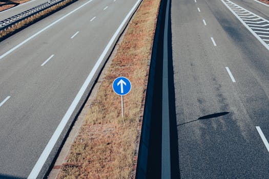Aerial view of an empty highway highlighting a traffic sign with an arrow, emphasizing direction and transportation infrastructure.